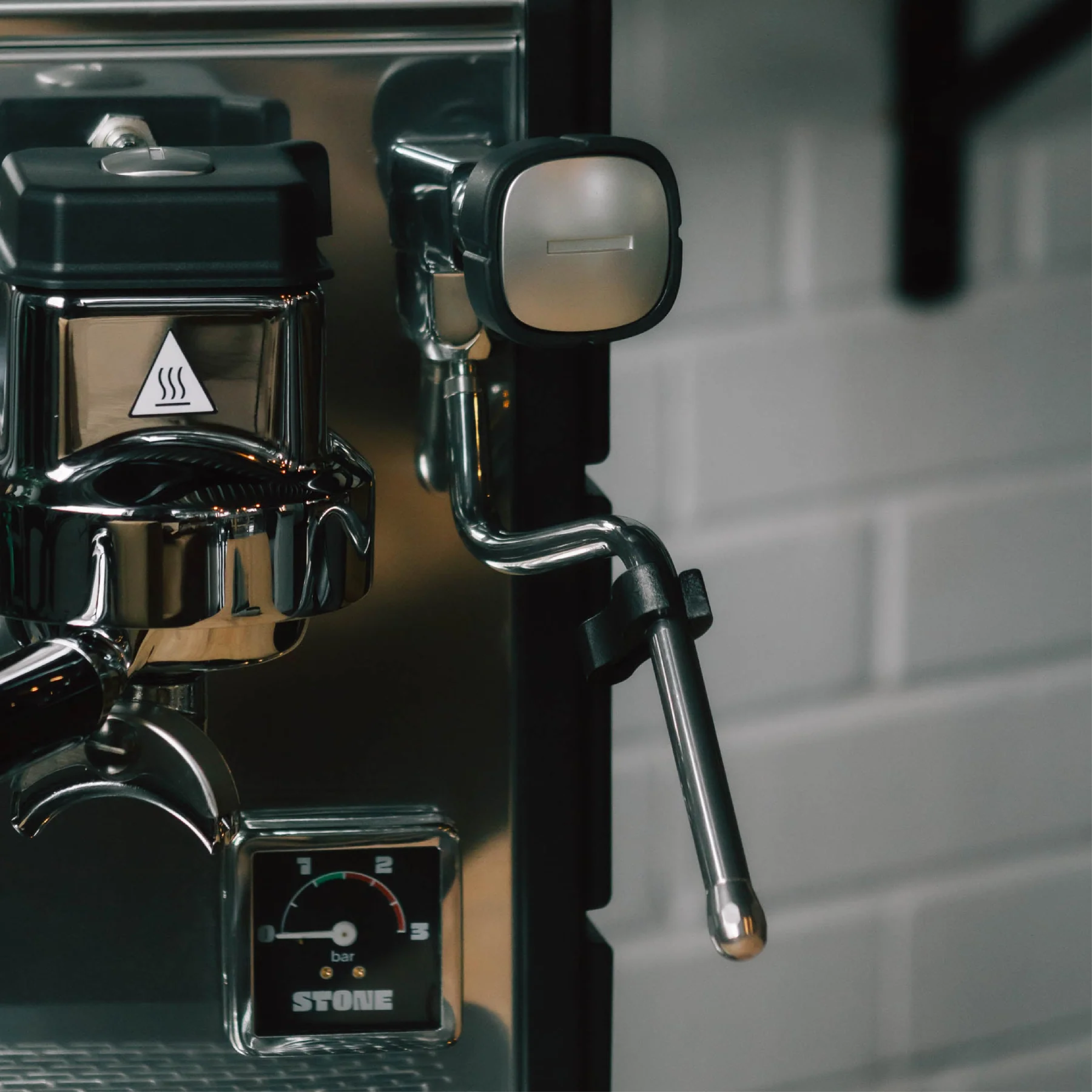 Stone Espresso Machine in plus black. Close up front view of the grouphead, steamwand and pressure gauge.